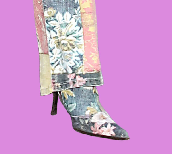 A stylish floral boot with a pointed toe and a small heel, part of a colorful patchwork outfit, bla bla.