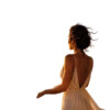 A woman with curly hair wearing a flowing beige dress, standing with her back to the camera, against a white background. bla bla.